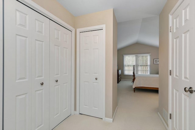 bedroom with baseboards, lofted ceiling, and light carpet