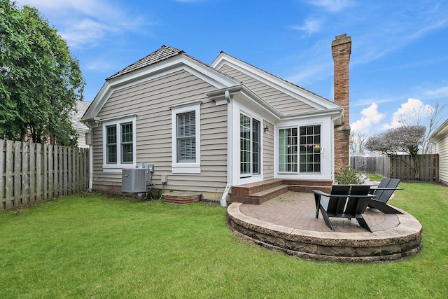 rear view of property with a fenced backyard, central AC, a yard, and a patio area