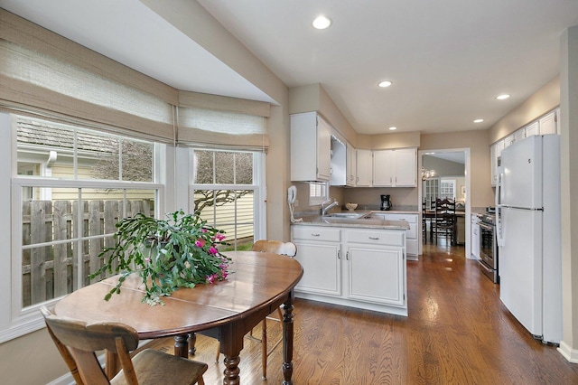 kitchen with light countertops, dark wood finished floors, white cabinetry, a sink, and freestanding refrigerator