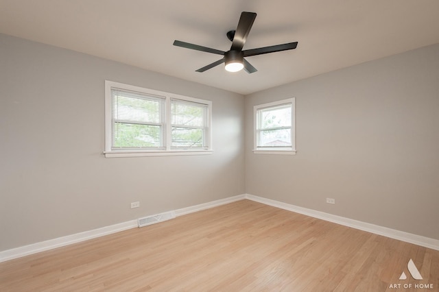 spare room featuring a ceiling fan, baseboards, light wood finished floors, and visible vents