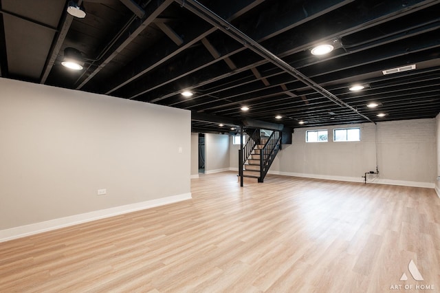 below grade area with baseboards, stairs, and wood finished floors