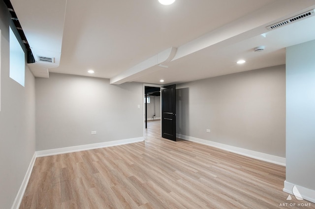 finished basement featuring light wood finished floors, baseboards, and visible vents