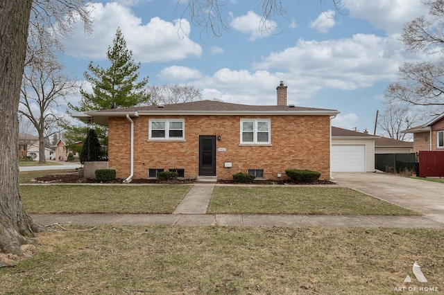 split foyer home featuring a chimney, a garage, concrete driveway, a front yard, and brick siding