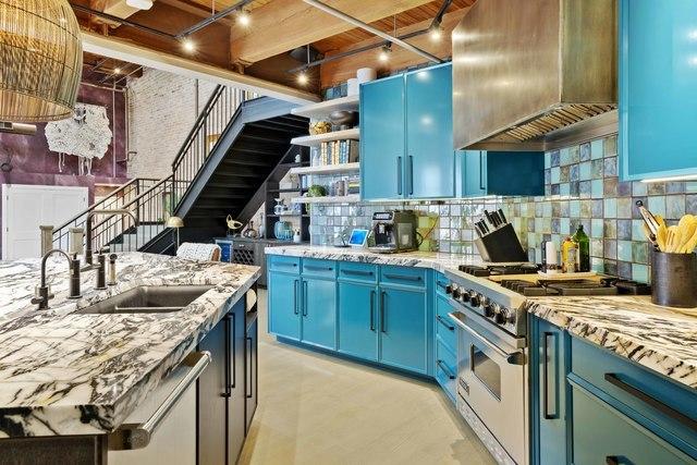 kitchen with blue cabinetry, high end stove, a sink, and premium range hood