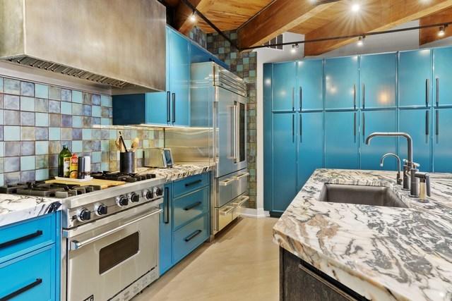 kitchen with a sink, high quality appliances, premium range hood, and blue cabinetry