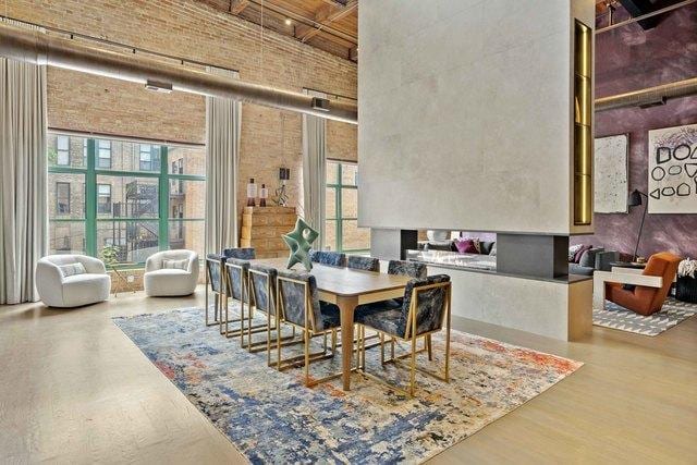 dining area with wood finished floors, a towering ceiling, and brick wall