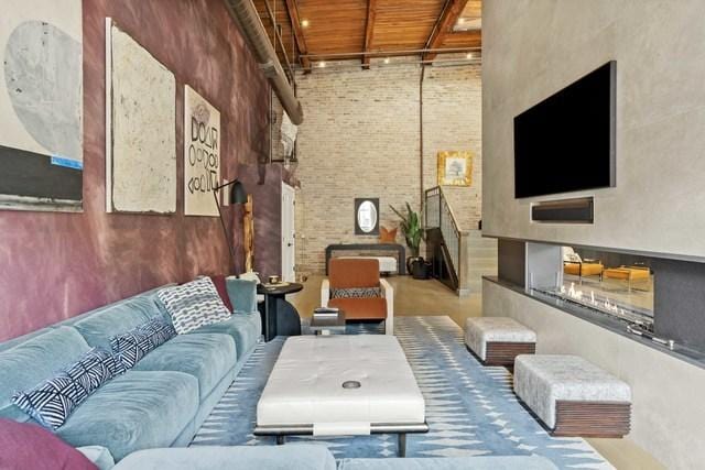 living area with a towering ceiling, wooden ceiling, and brick wall