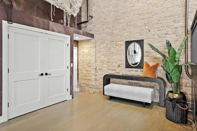 sitting room with a towering ceiling, wood finished floors, and brick wall
