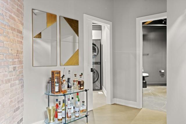 hall with baseboards, stacked washer / dryer, and brick wall