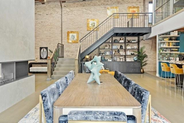 dining space featuring a high ceiling, stairway, and brick wall