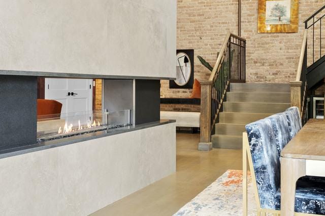 interior space featuring a fireplace, concrete floors, brick wall, and a towering ceiling