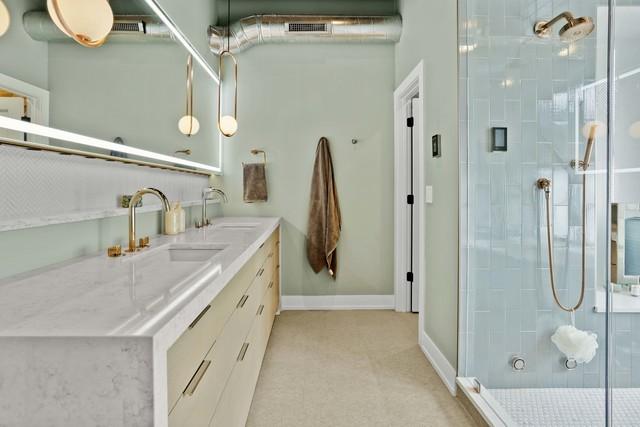 bathroom with a sink, a shower stall, baseboards, and visible vents
