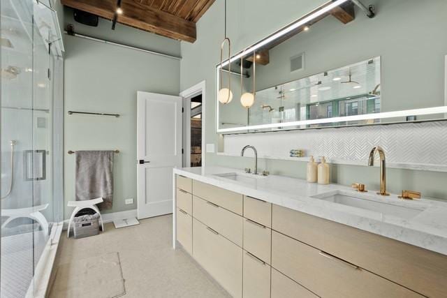 full bathroom with double vanity, a sink, a stall shower, and beamed ceiling
