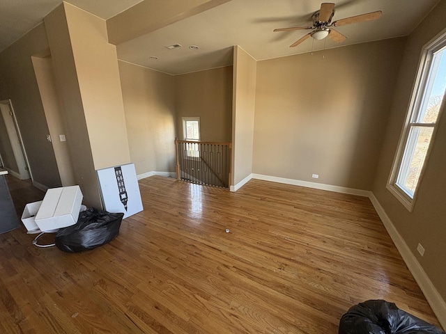 unfurnished room with baseboards, wood finished floors, a healthy amount of sunlight, and a ceiling fan