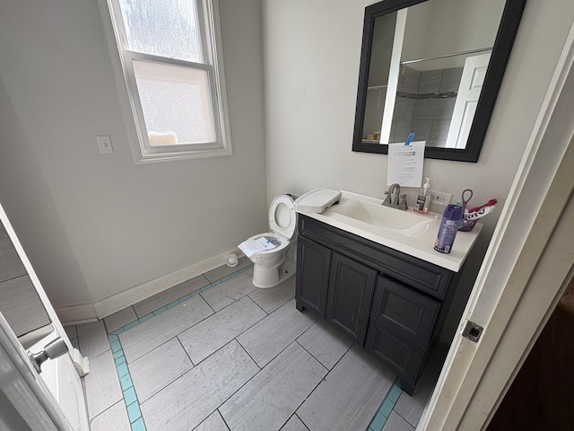 bathroom with baseboards, toilet, and vanity