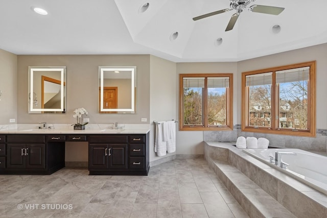 bathroom with a sink, double vanity, lofted ceiling, ceiling fan, and a garden tub