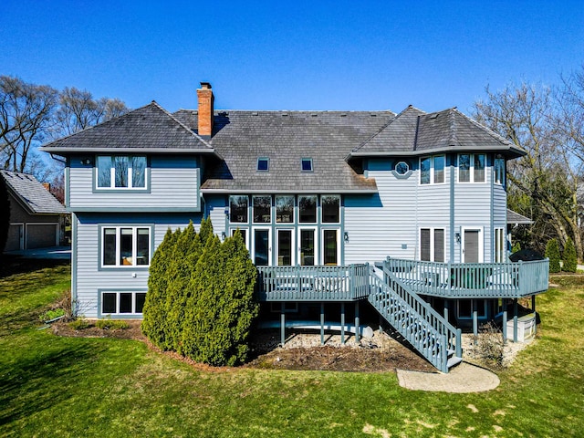 rear view of property featuring a lawn, a chimney, and a deck