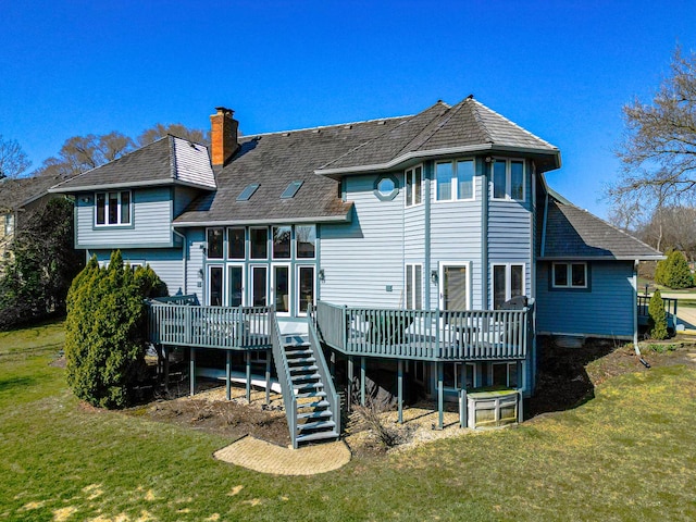 back of property featuring a chimney, a wooden deck, a yard, and stairs