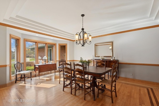 dining space with a chandelier, a raised ceiling, light wood-style flooring, and baseboards