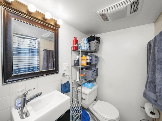 2124 W 24th St, Chicago, IL 60608 - full bath with toilet, a sink, visible vents, decorative backsplash, and tile walls