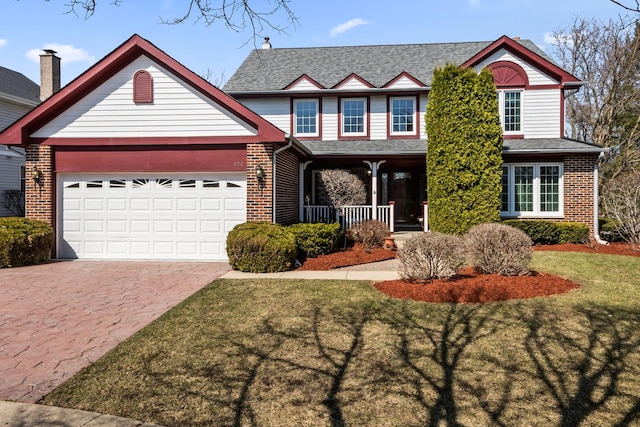 traditional home with driveway, covered porch, a front yard, a garage, and brick siding