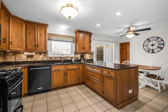 kitchen with a peninsula, a sink, backsplash, brown cabinetry, and black appliances