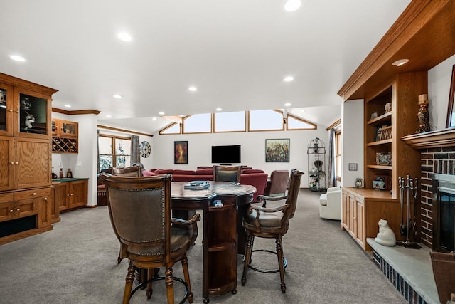 dining room featuring recessed lighting, lofted ceiling, a brick fireplace, and light carpet