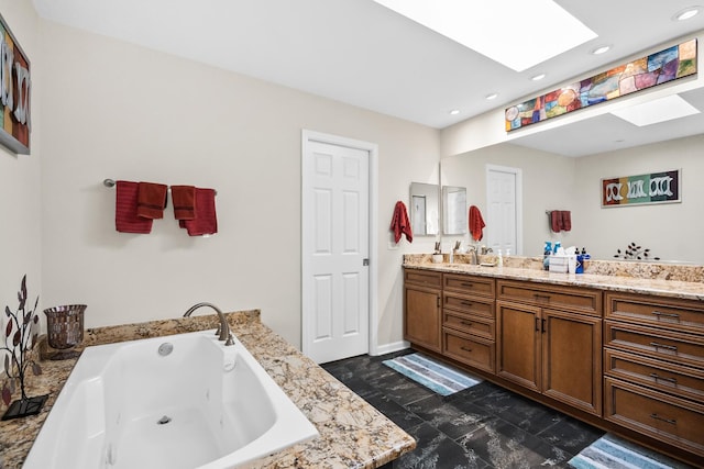 bathroom with recessed lighting, a jetted tub, double vanity, and a skylight