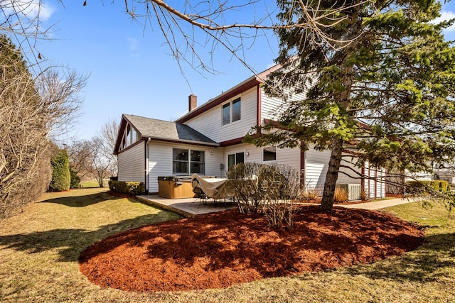 rear view of house with a chimney, a yard, a patio, and a shingled roof