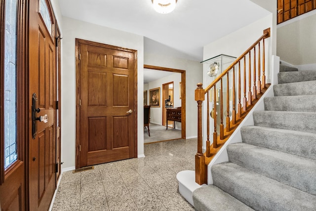 foyer featuring granite finish floor, baseboards, and stairway