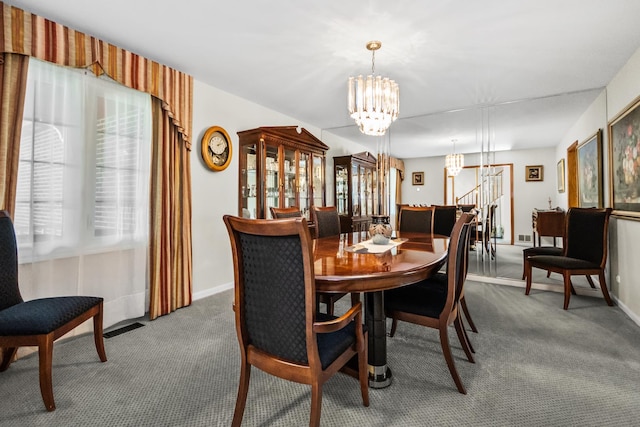 carpeted dining area featuring visible vents, baseboards, and a chandelier