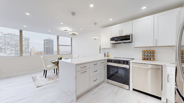 kitchen with white cabinets, light countertops, stainless steel appliances, decorative light fixtures, and a peninsula