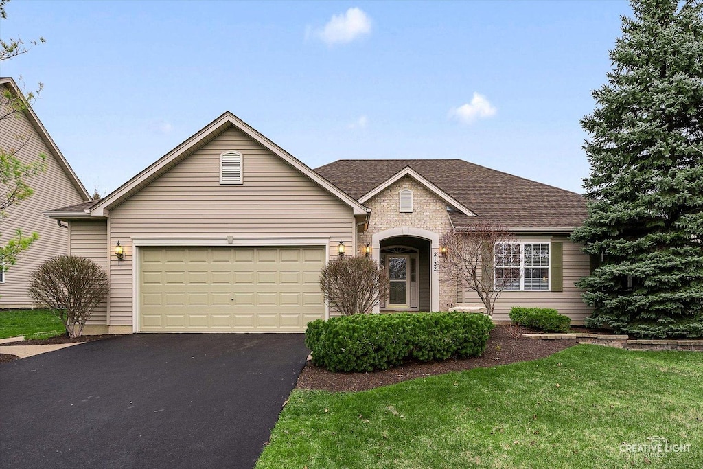 2132 James Leigh Dr, Aurora, IL 60503 - view of front facade with a front yard, an attached garage, a shingled roof, and aphalt driveway