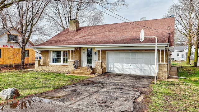 view of front of house featuring aphalt driveway, a chimney, a garage, brick siding, and roof with shingles
