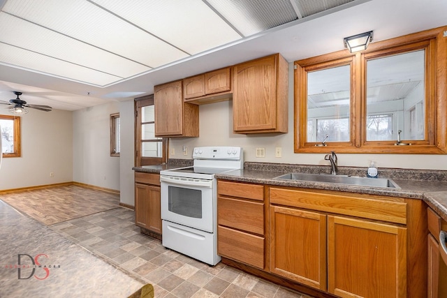 kitchen with a sink, a ceiling fan, baseboards, dark countertops, and electric range