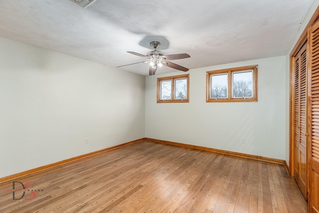 unfurnished bedroom with a closet, baseboards, light wood-style floors, and ceiling fan