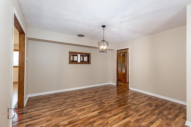 empty room featuring baseboards, a notable chandelier, and dark wood-style flooring