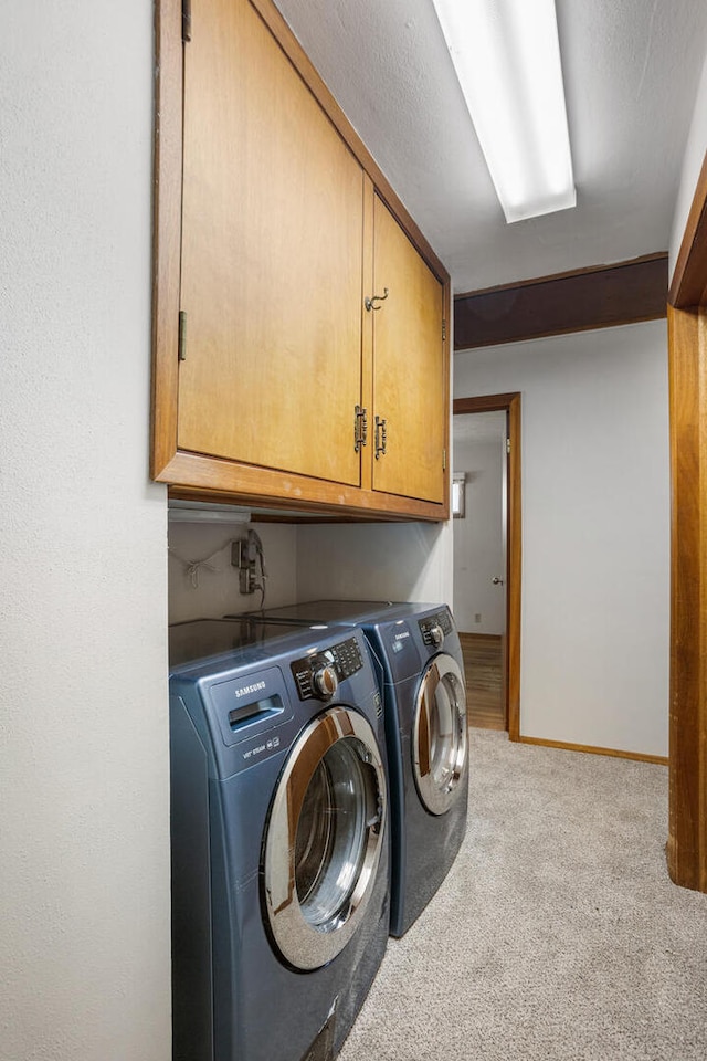 clothes washing area with washer and clothes dryer, cabinet space, baseboards, and carpet floors