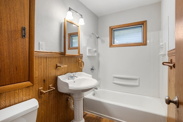 full bath featuring toilet, tub / shower combination, wainscoting, and wood finished floors
