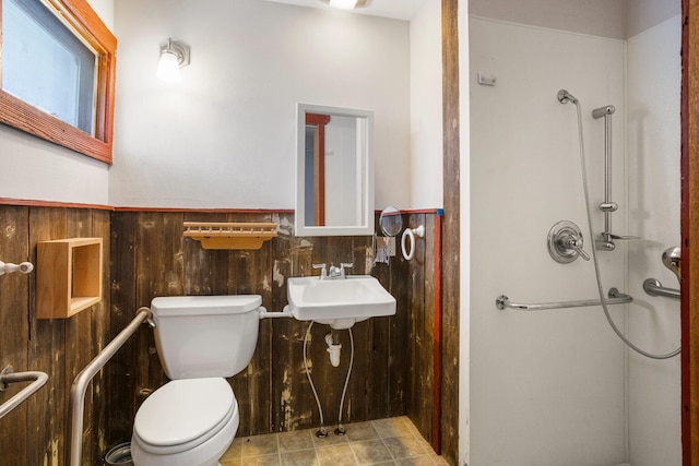 bathroom with toilet, a sink, a shower stall, and wainscoting
