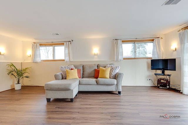 living area featuring visible vents, wainscoting, and wood finished floors