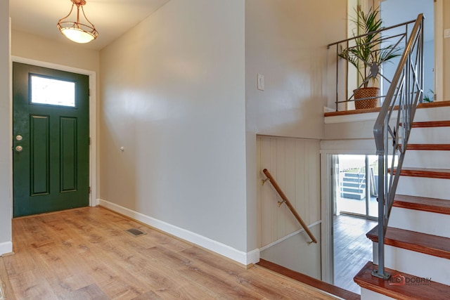 foyer entrance with a wealth of natural light, visible vents, wood finished floors, and baseboards
