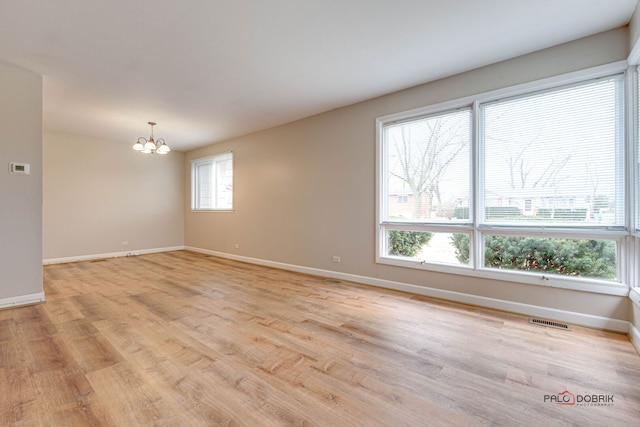 spare room featuring baseboards, visible vents, an inviting chandelier, and light wood-type flooring