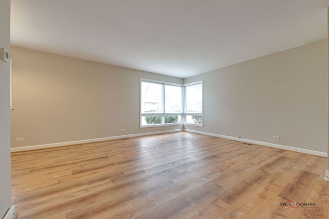empty room with baseboards and light wood-style floors