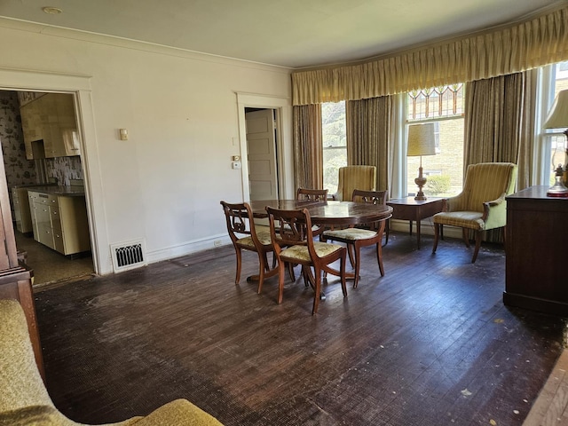 dining space with baseboards, visible vents, dark wood-style floors, and crown molding