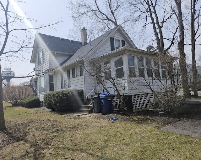 view of property exterior featuring a lawn, a shingled roof, and a chimney