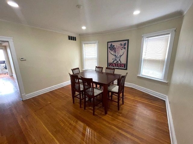 dining area featuring visible vents, crown molding, baseboards, and wood finished floors