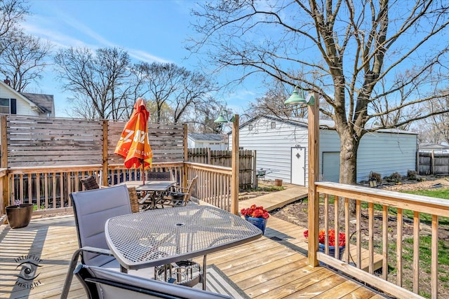 wooden deck featuring outdoor dining area, an outdoor structure, and fence
