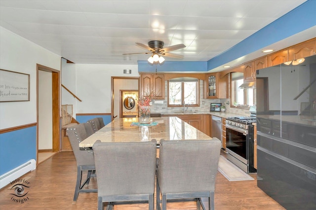 kitchen featuring a kitchen bar, a center island, a sink, stainless steel appliances, and a baseboard radiator