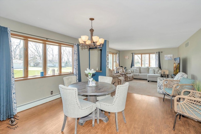 dining space featuring visible vents, a notable chandelier, light wood-style floors, and a baseboard heating unit